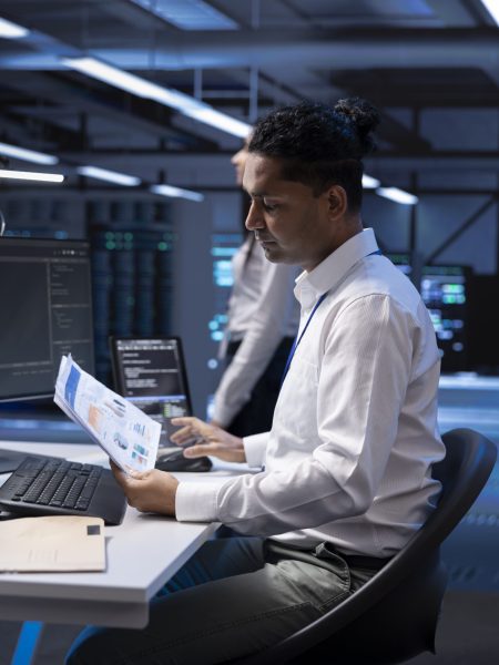 Serviceman in server hub checking documentation of supercomputers used for computationally intensive tasks such as scientific simulations or 3D rendering, doing annual equipment checkup